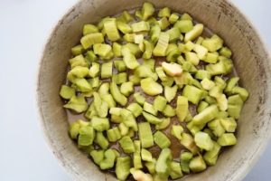 Préparation gâteau à la rhubarbe, beurre et sucre roux recouverts de rhubarbe.