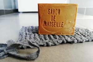 Gros plan sur l'éponge tawashi avec un savon de Marseille dessus