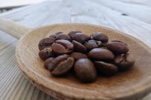 Grains de café dans une cuillère en bois.