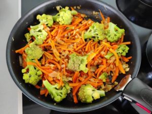 Poêle avec les légumes : carottes, ail, oignons et chou romasneco